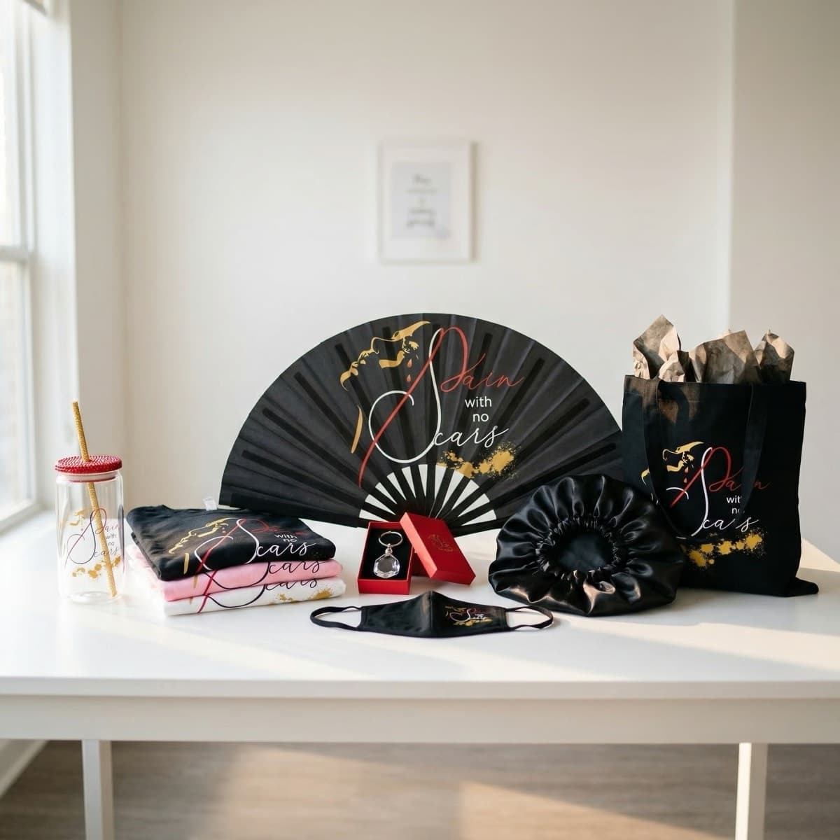 Pain With No Scars merchandise: t-shirts, tote bag, hand fan, crystal keychain, satin bonnet, face mask, and faith tumbler